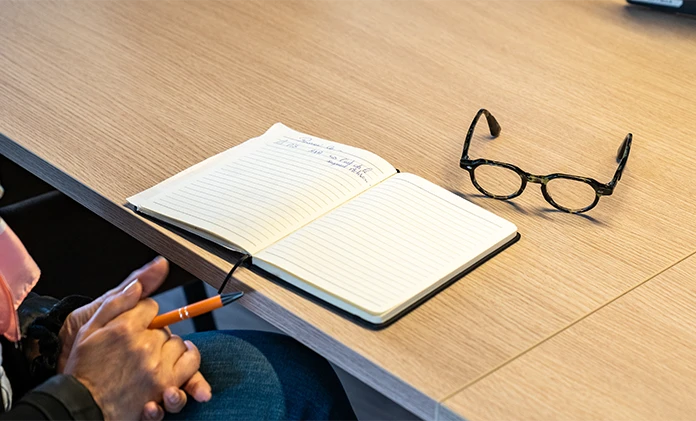 Carnet de notes ouvert et lunettes posés sur un bureau en bois, illustrant le lexique et les définitions de l'assurance.
