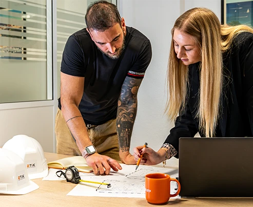Souscripteurs experts analysant des plans avec des casques de chantier pour l'assurance des professionnels du bâtiment.