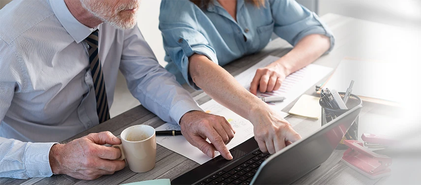 Collaborateurs analysant des graphiques sur un ordinateur de bureau, illustrant l’assurance prévoyance.