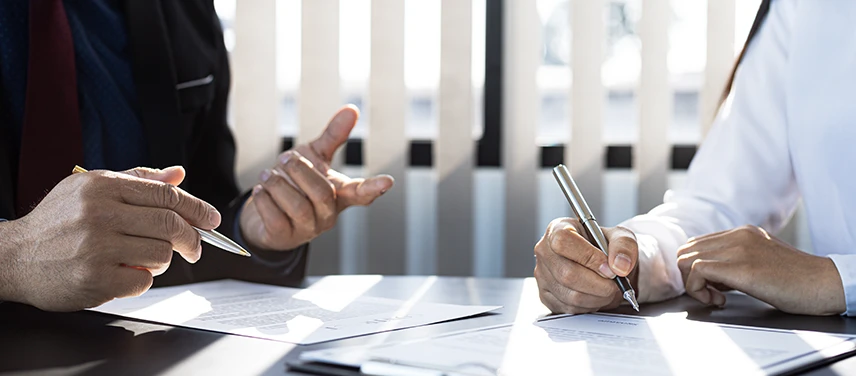 Échange et signature de documents entre un conseiller et un professionnel, illustrant l’assurance santé.